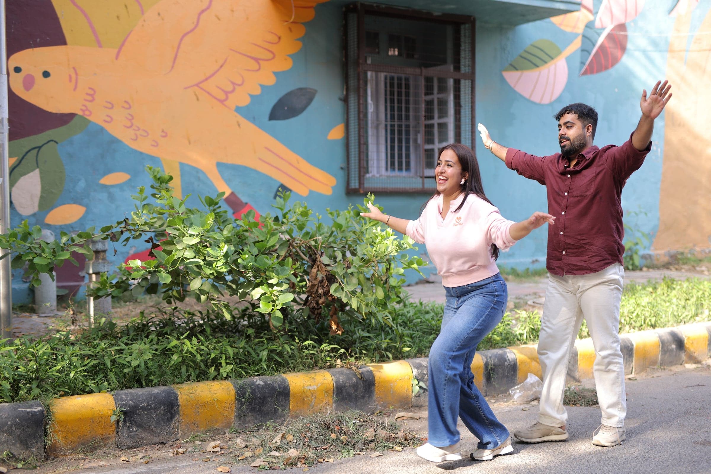 Disha and Mayank dancing in front of a painted wall