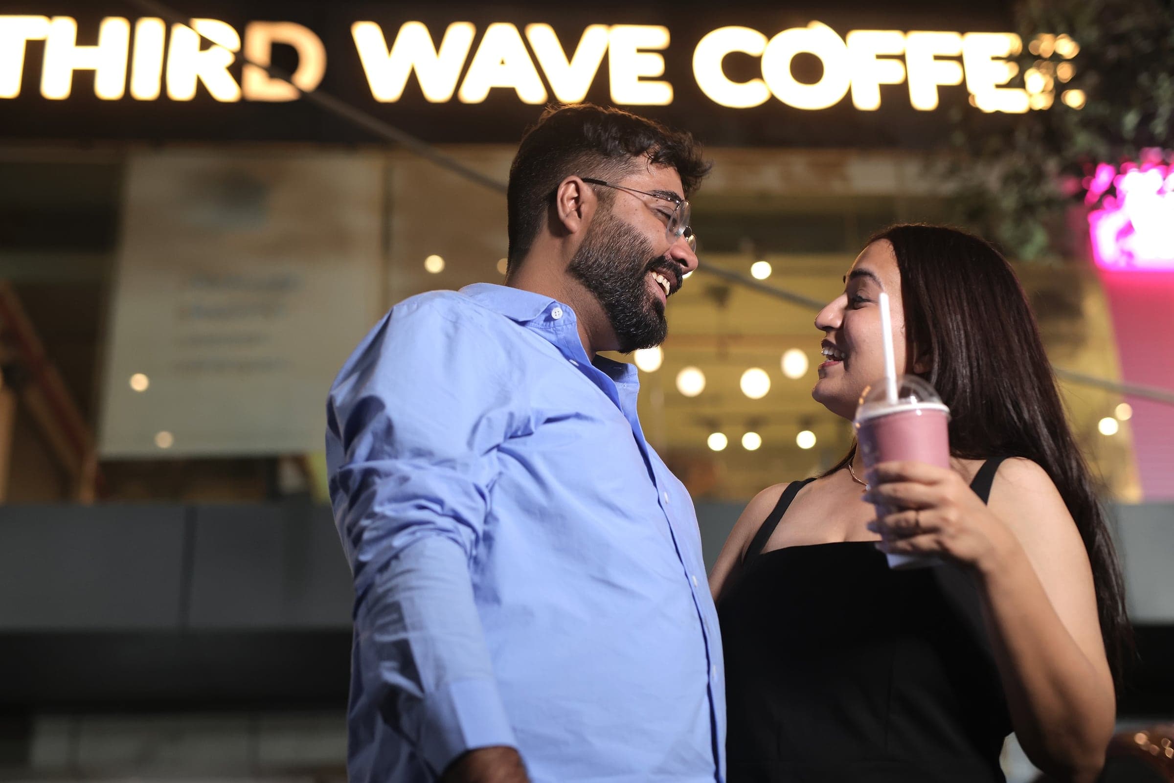 Disha and Mayank laughing outside a café at night