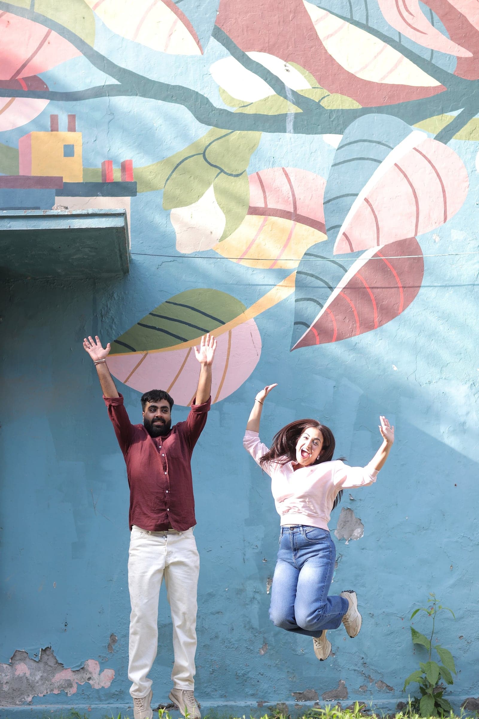 Disha and Mayank jumping in front of a mural